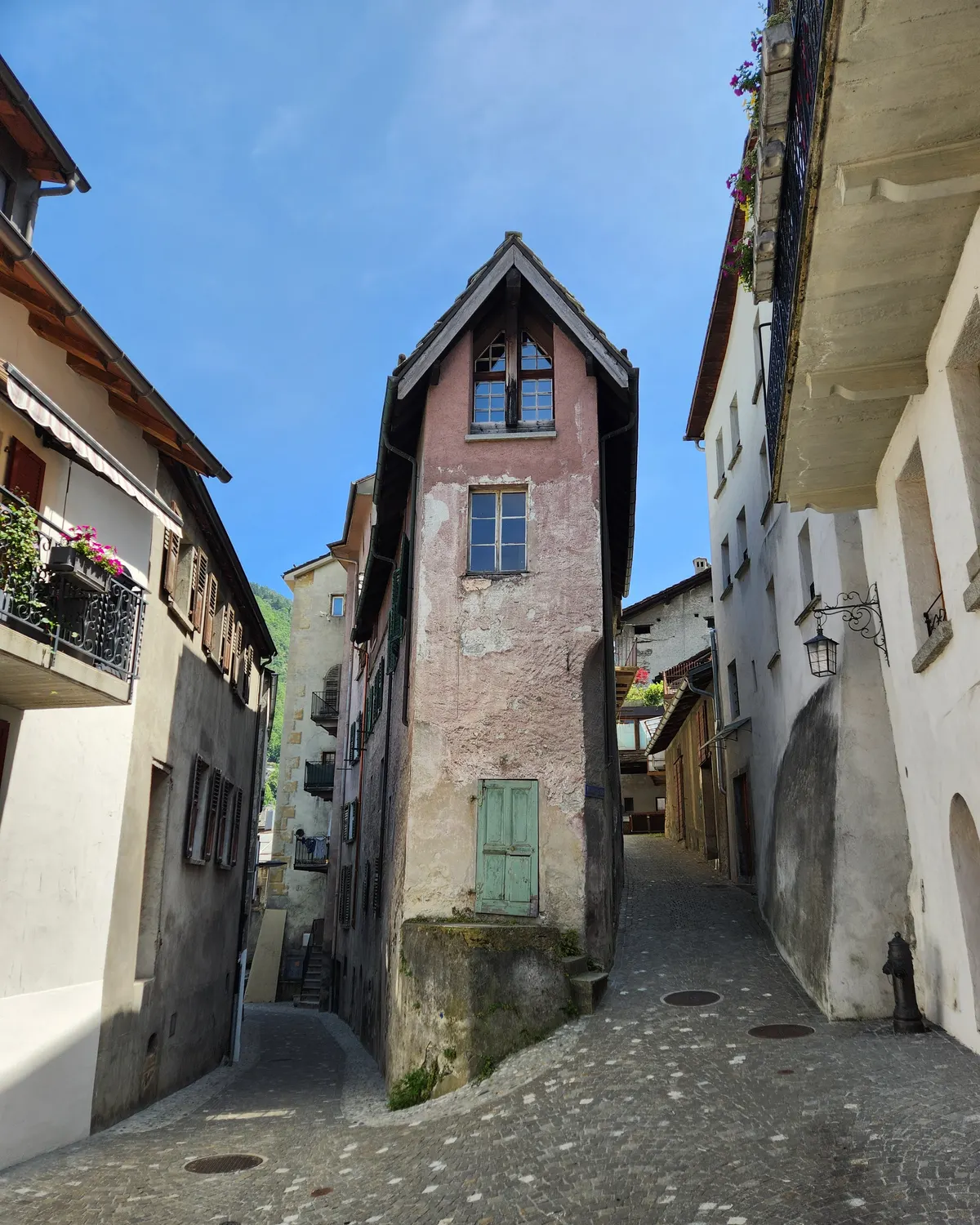 Narrow old street in Visp with historic buildings and blue sky.