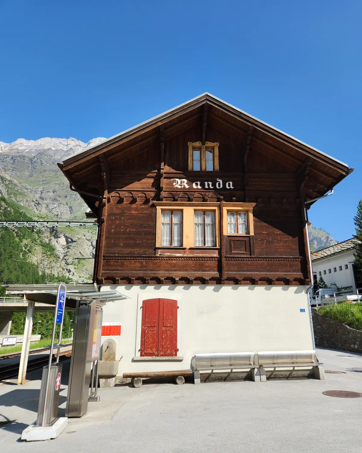 Traditional wooden building at Randa station with mountains behind.